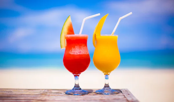 Two tasty fruits cocktails on background of turquoise sea — Stock Photo, Image