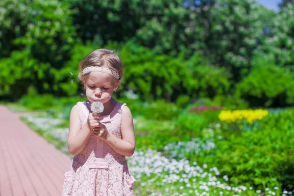 Little girl blowing a dandelion outdoor — Stock Photo, Image
