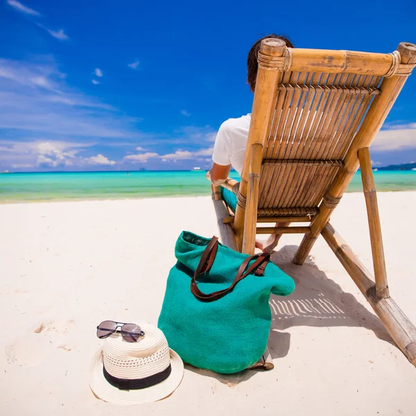 Hombre joven relajándose en silla de madera en la playa de arena blanca — Foto de Stock