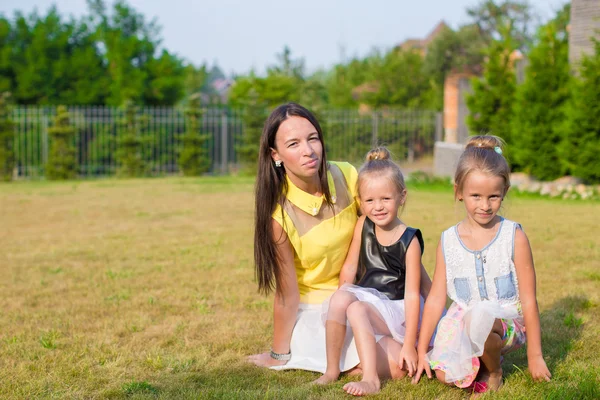 Moeder en kinderen zitten buiten in mooie zomerse park — Stockfoto