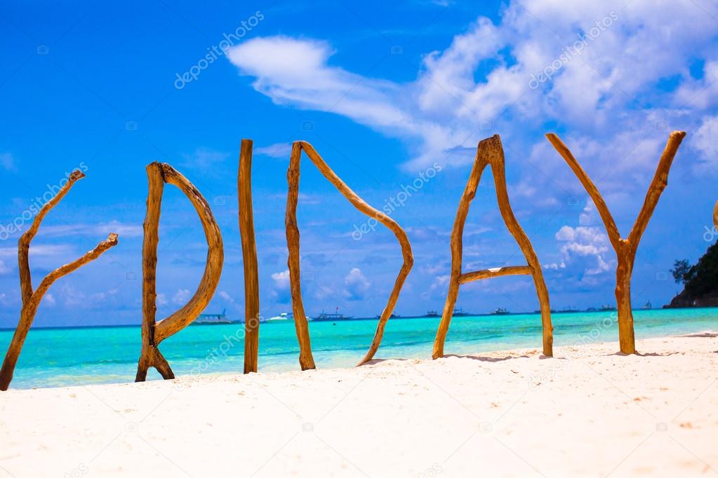 Perfect white sandy beach and turquoise sea on tropical island with wooden letters made Friday word