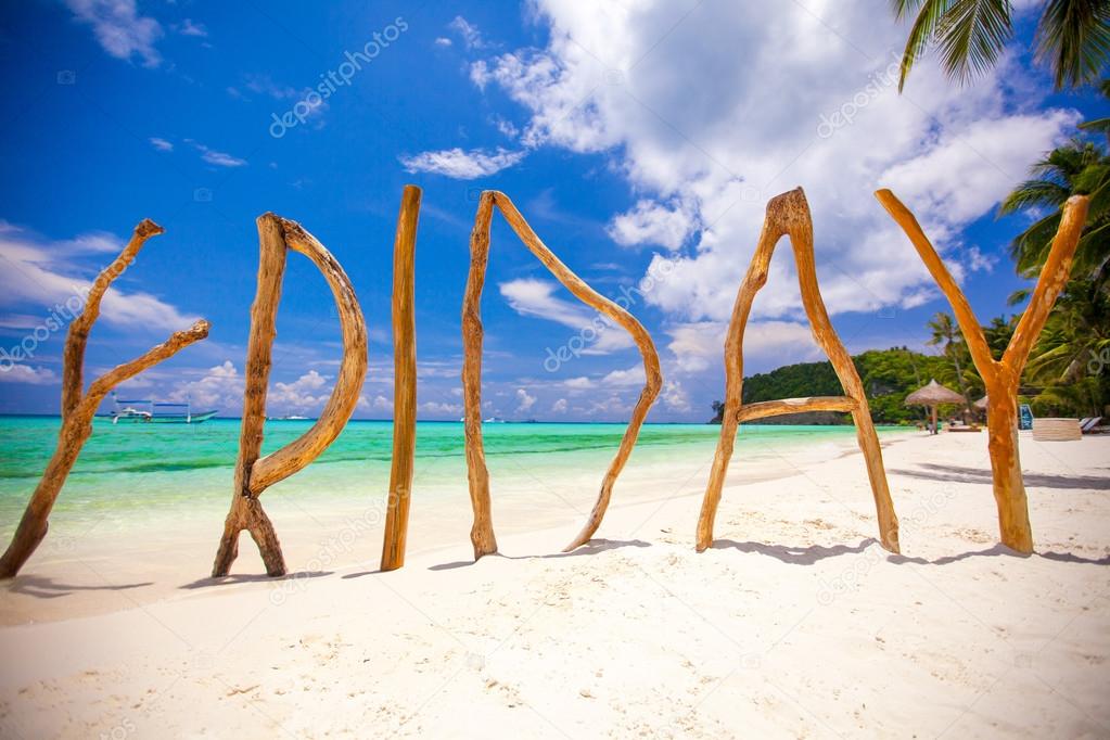 Perfect white sandy beach and turquoise sea on tropical island with wooden letters made Friday word