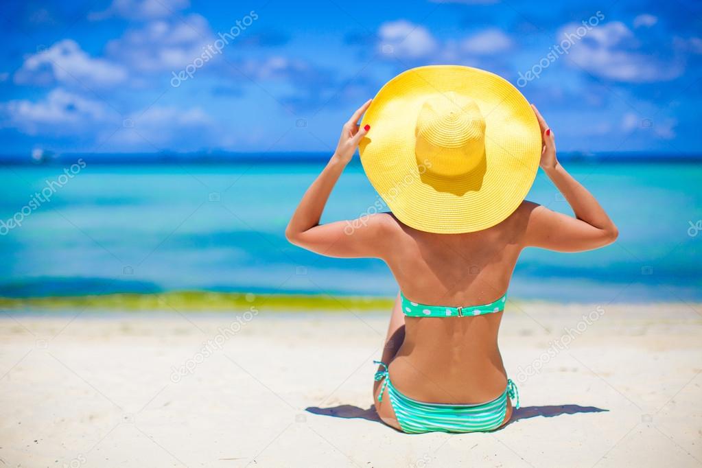 Beautiful woman in yellow hat on white tropical beach