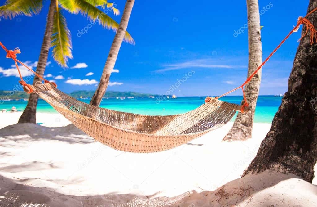 Straw hammock on tropical white sandy beach