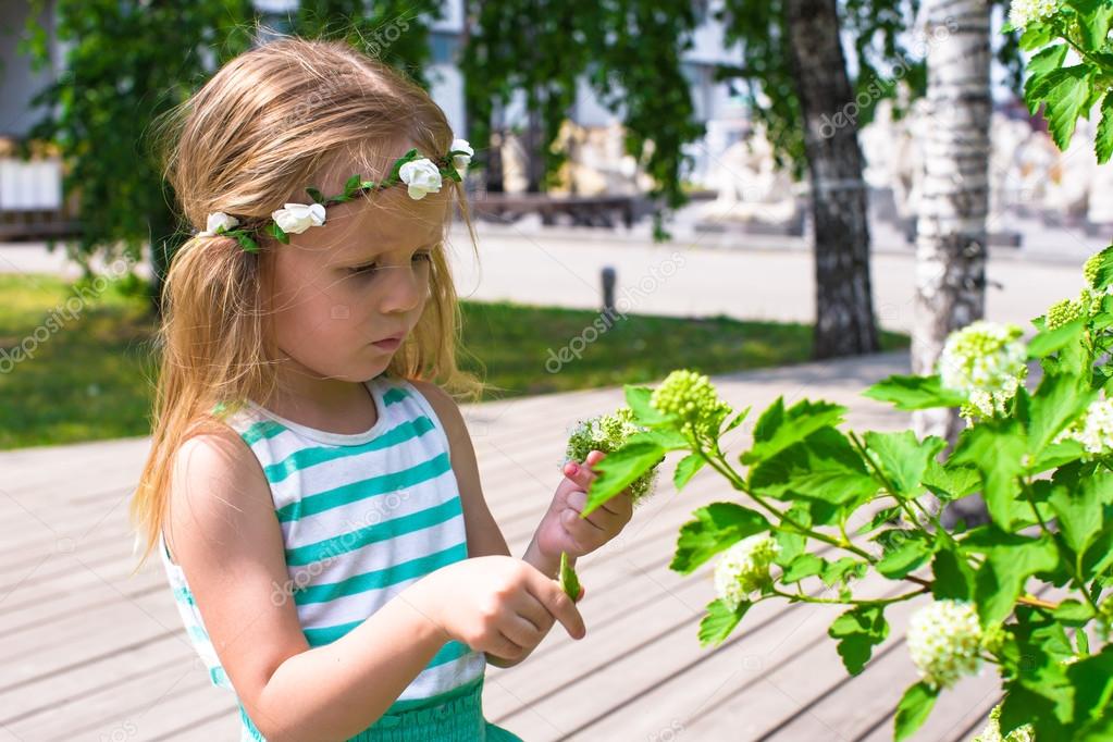 Little adorable girl near white flowers in the garden