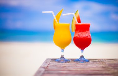 İki kokteyl taze karpuz ve mango turkuaz Denizi çarpıcı arka plan üzerinde