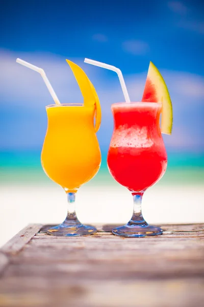 Two tasty fruits cocktails on background of turquoise sea — Stock Photo, Image