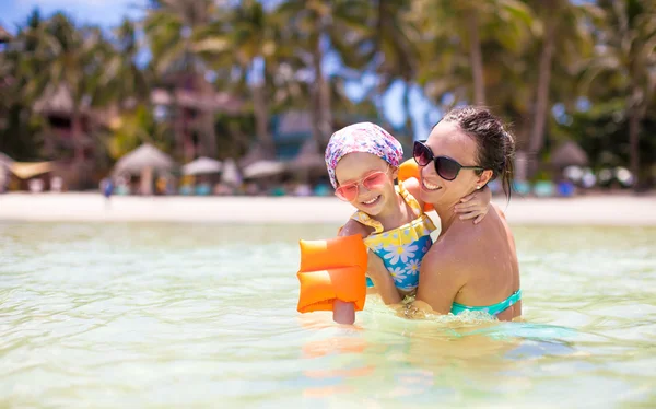 Entzückendes kleines Mädchen und glückliche Mutter schwimmen im klaren Meer — Stockfoto