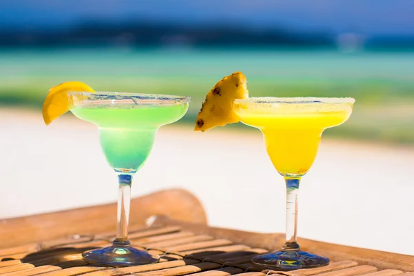 Two tasty alcoholic cocktails on background of turquoise sea — Stock Photo, Image