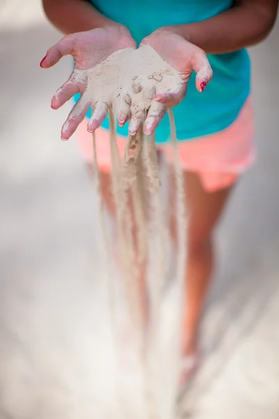 Sable blanc à travers les doigts de la jeune fille — Photo