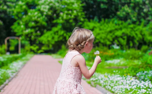 Malá holčička foukání Pampeliška venkovní — Stock fotografie