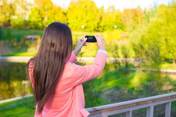 若い女性は、秋の日に彼女の携帯電話で写真を撮る — ストック写真