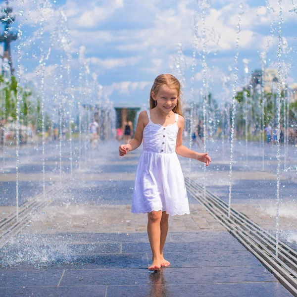 Menina bonito se divertindo na fonte ao ar livre no dia quente — Fotografia de Stock