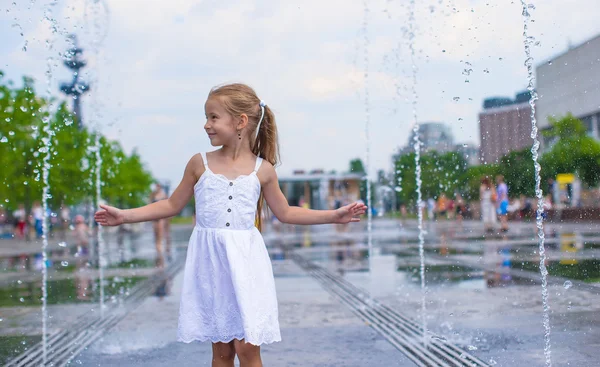 Kleines glückliches Mädchen hat Spaß im Brunnen im Freien bei heißem Tag — Stockfoto