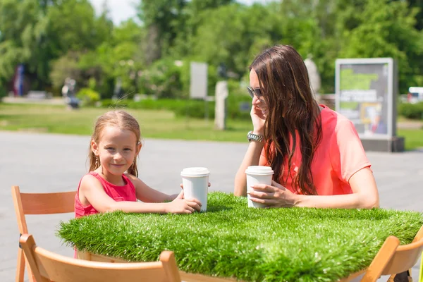 Joven madre y su pequeña niña en la cafetería al aire libre en el día cálido —  Fotos de Stock