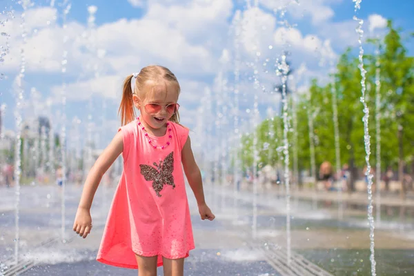 Liten flicka spelar i öppna gatan fontän på varm solig dag — Stockfoto