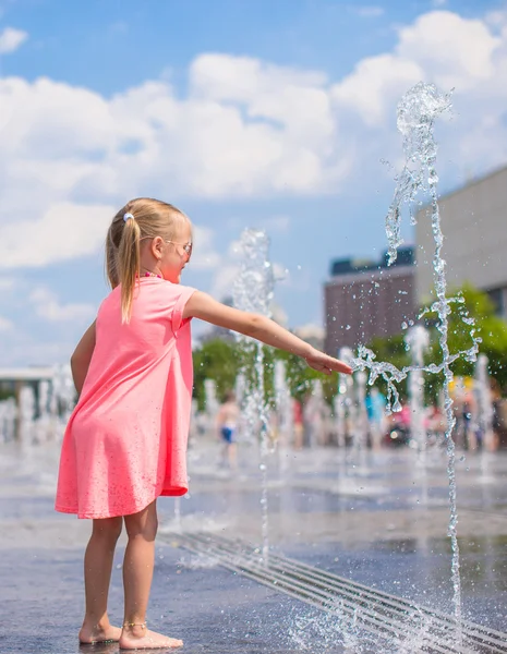 Bambina che gioca in una fontana aperta in una calda giornata di sole — Foto Stock