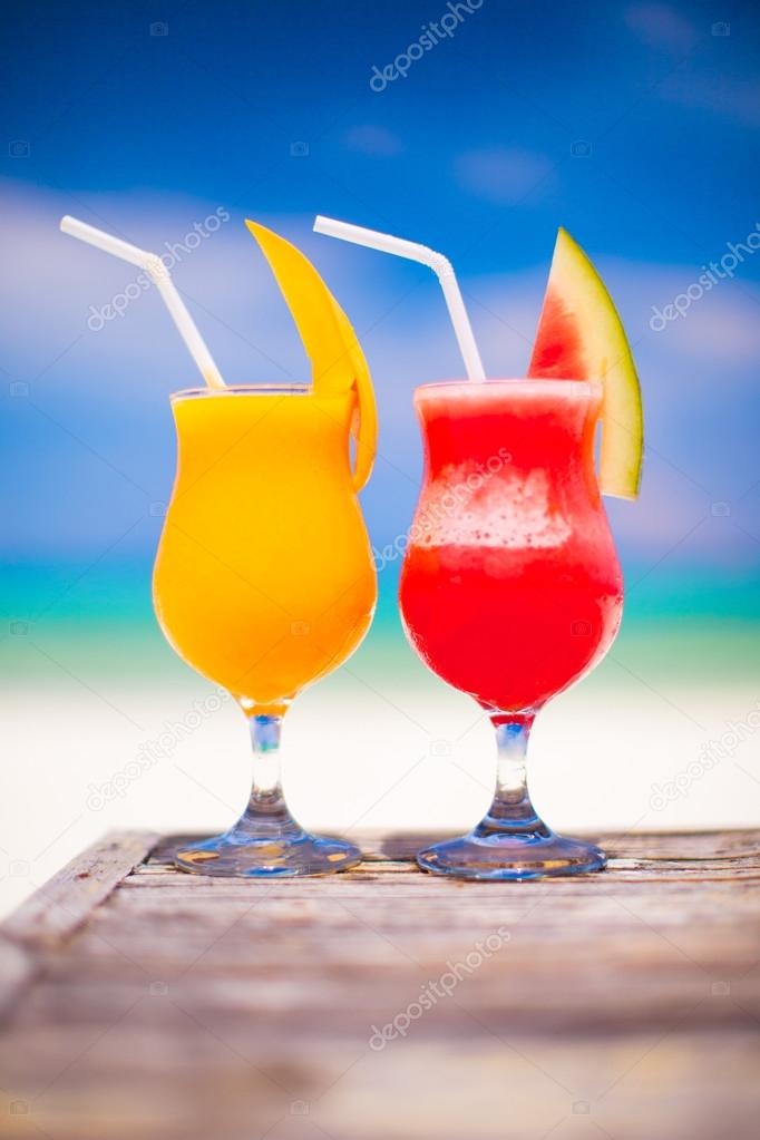 Two tasty fruits cocktails on background of turquoise sea