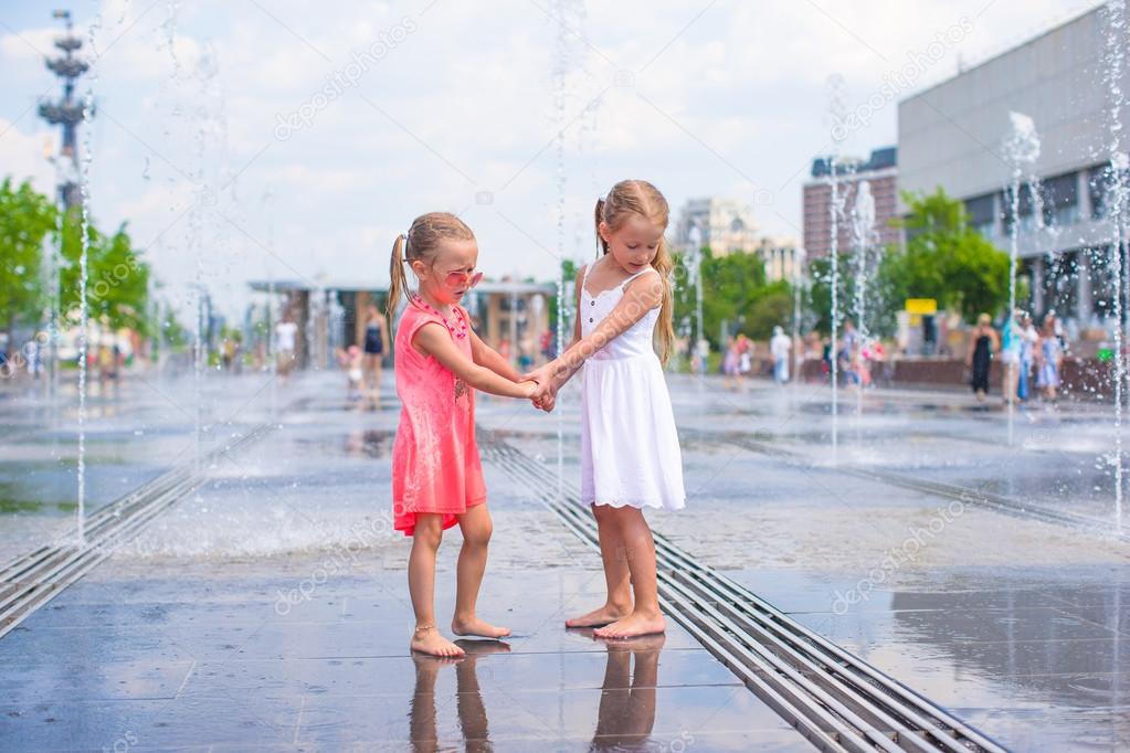 Little girls enjoy sunny day in outdoors fountain