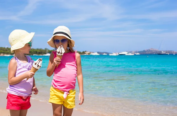 Маленькие счастливые девочки едят мороженое на тропическом пляже — стоковое фото