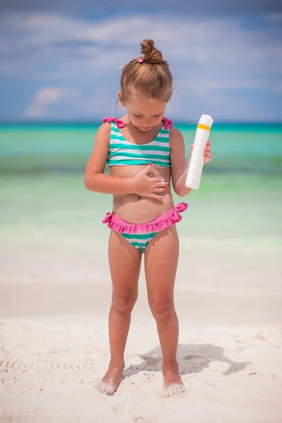 Little adorable girl in swimsuit with suntan lotion bottle — Stock Photo, Image