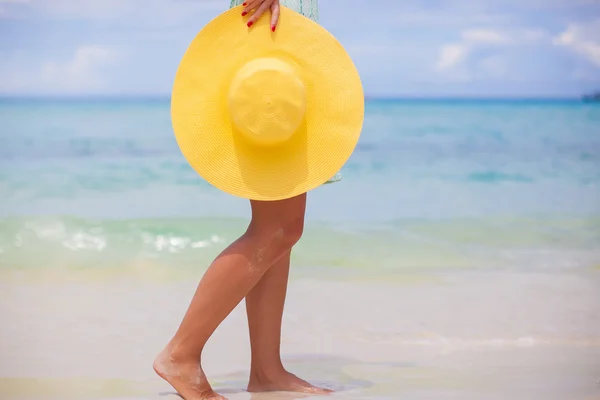 El primer plano del sombrero amarillo a las manos femeninas en la playa — Foto de Stock