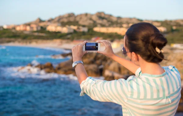 Genç kadın beach tatil sırasında telefonla bir resim çekmek — Stok fotoğraf