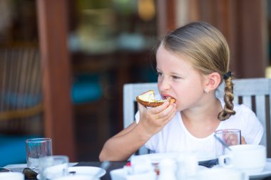 Tereyağı ve bal ile ekmek üzerinde kahvaltı küçük sevimli kız