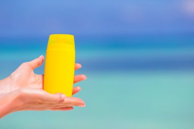 Suncream şişe arka plan mavi deniz ile eller