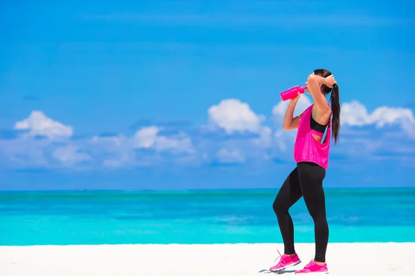 Přizpůsobit mladá žena dělá cvičení na tropické bílé pláži ve svém sportovním oblečení — Stock fotografie