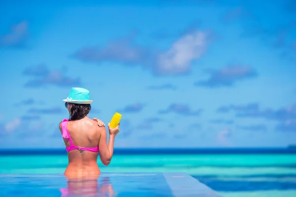 Mujer joven aplicando crema solar durante las vacaciones en la playa —  Fotos de Stock