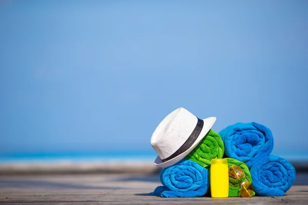 Beach and summer vacation accessories concept - close-up of colorful towels, hat and sunscreen — Stock Photo, Image