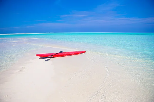 Red surfboard on white sandy beach with turquoise water — Stock Photo, Image