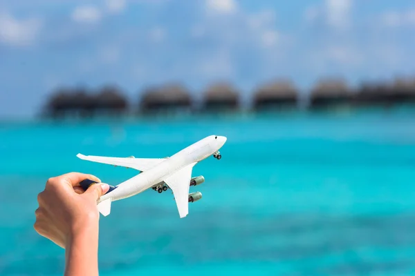 Маленький белый игрушечный самолет на тропическом пляже фоновом бунгало воды — стоковое фото
