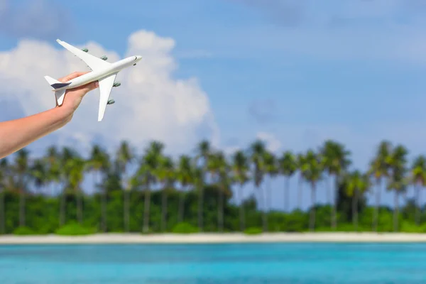 Small white toy airplane on tropical beach in human hand — Stock Photo, Image