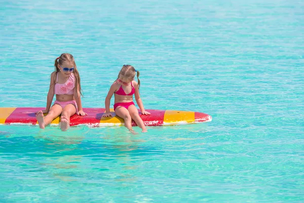 Urocze dziewczynki na deskę surfingową w turkusowe morze — Zdjęcie stockowe