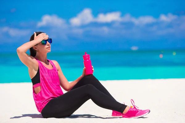 Fit jonge vrouw op tropische witte strand in haar sportkleding — Stockfoto