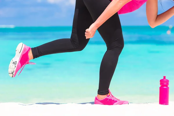 Close-up van vrouwelijke benen in sneakers uitgevoerd op witte zandstrand — Stockfoto
