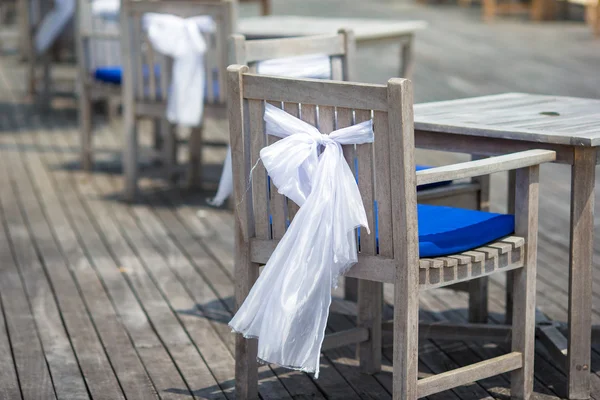 Svatební židle zdobené bílými mašlemi na venkovní kavárna — Stock fotografie