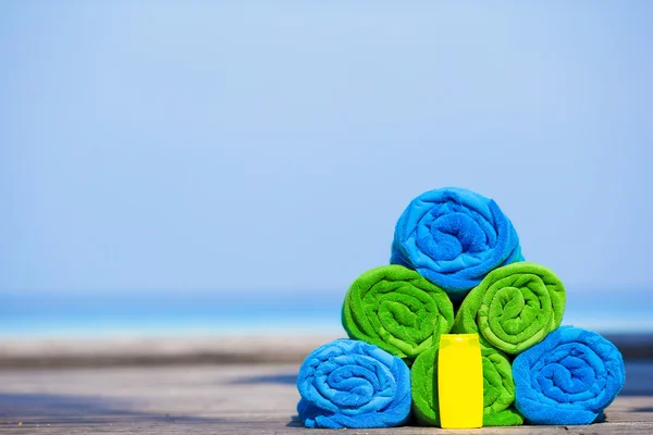 Close up of colorful towels and sunscreen bottle background the sea — Stock Photo, Image