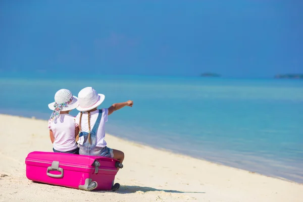 Aranyos kislány a trópusi fehér strand nyaralás során nagy bőrönddel — Stock Fotó