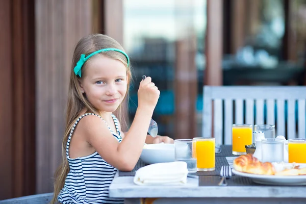 Liebenswertes kleines Mädchen frühstückt im Café im Freien — Stockfoto