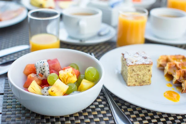 Ensalada de frutas frescas, gofres, tarta, café y jugo servido para el desayuno en el restaurante del resort —  Fotos de Stock