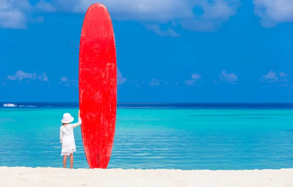 Adorable niña pequeña con tabla de surf grande roja durante las vacaciones tropicales — Foto de Stock