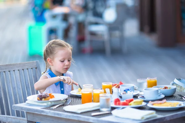 Adorable niña tomando el desayuno en la cafetería al aire libre —  Fotos de Stock