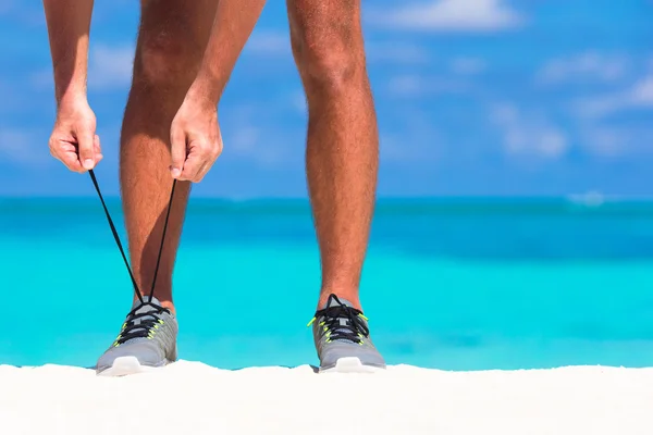 Joven corredor masculino preparándose para comenzar en la playa blanca — Foto de Stock