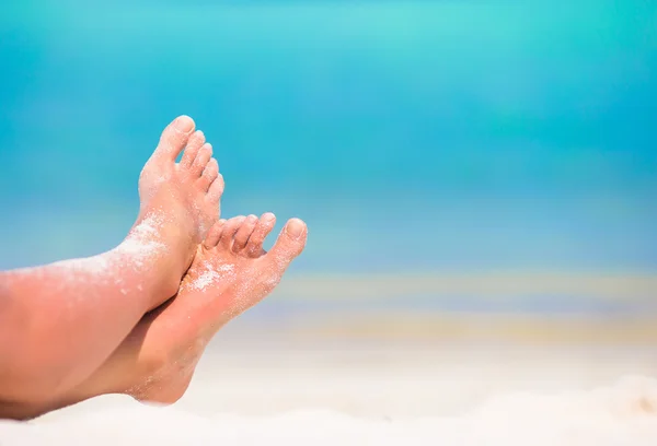 Närbild av kvinnliga fötter på vit sandstrand — Stockfoto