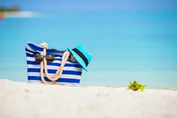 Borsa blu, cappello di paglia, occhiali da sole sulla spiaggia bianca — Foto Stock