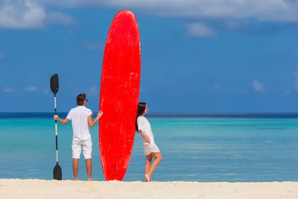 Młoda para z czerwony deska surfingowa podczas tropikalny wakacje — Zdjęcie stockowe