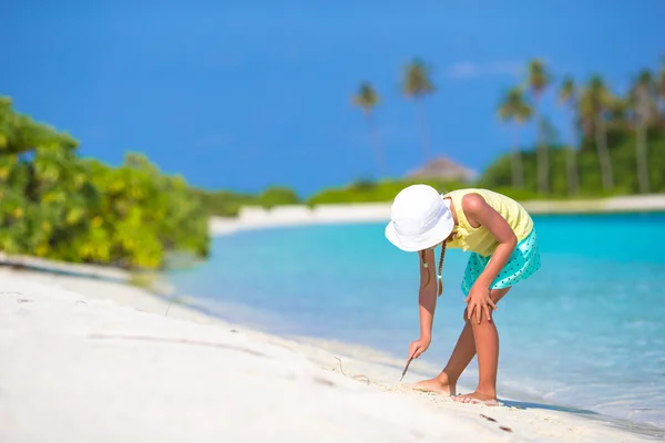 Adorable little girl drawing picture on white beach — Stock Photo, Image